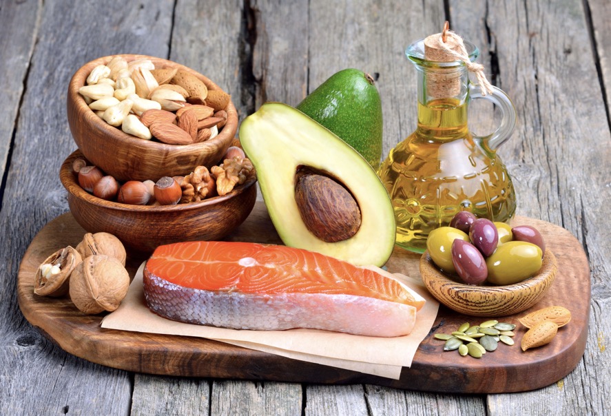 A selection of healthy fats including nuts, salmon, avocado and olive oil