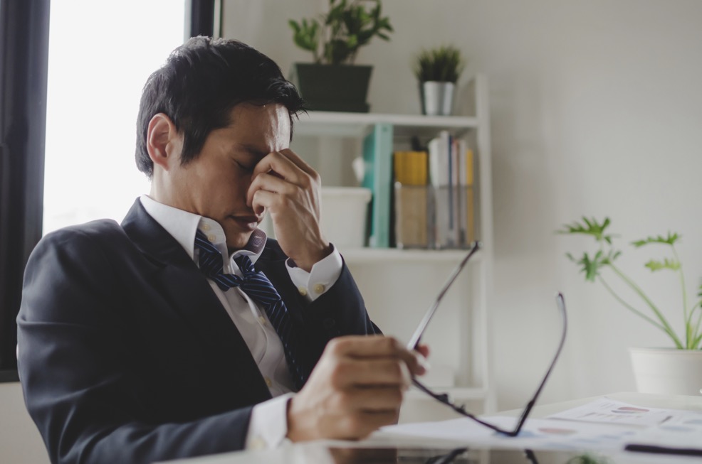 man in suit with post viral fatigue sitting at desk