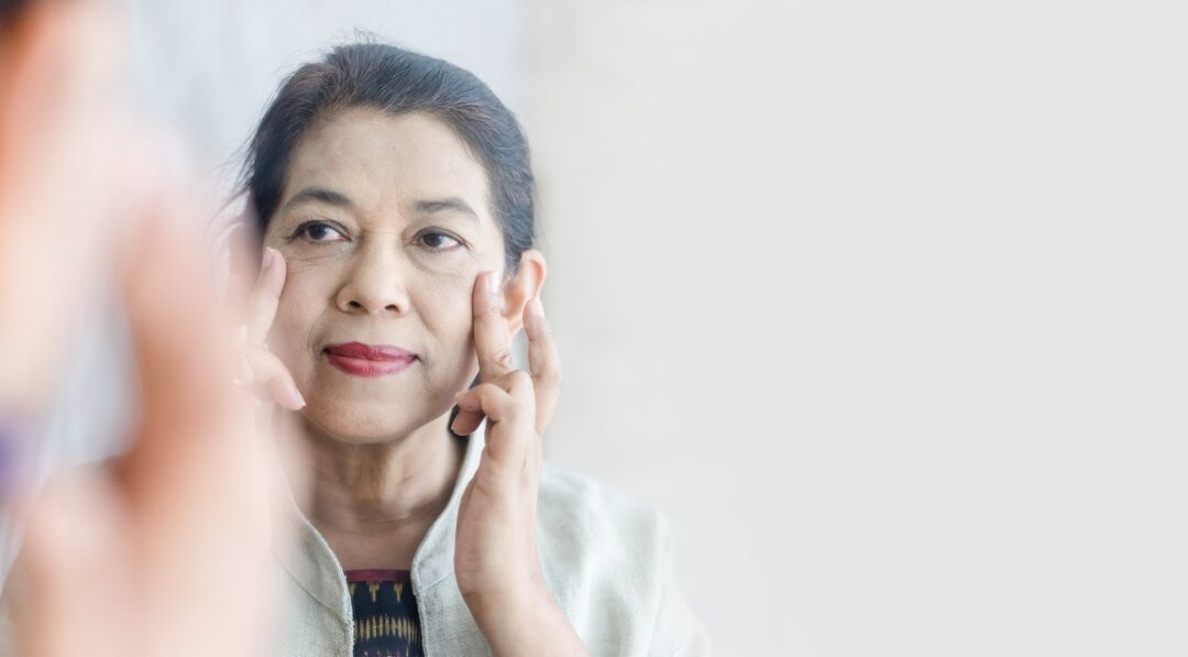 Perimenopause woman looking in mirror and supporting skin health