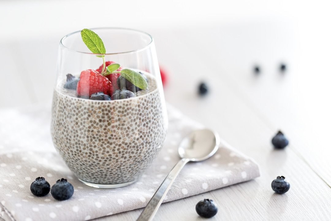 a glass of chia pudding with blueberries and strawberries