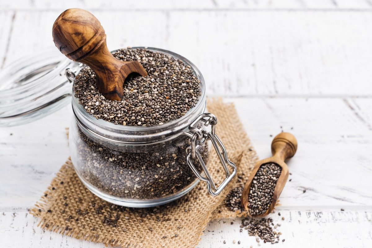 Black chia seeds in a glass jar with a wooden scoop