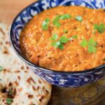 red lentil dahl in a blue bowl with naan